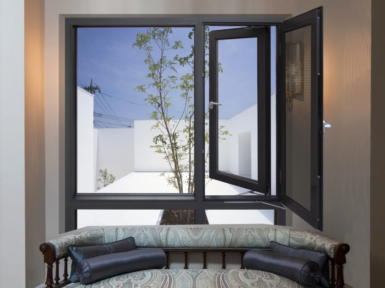 Open black-framed casement window above a sofa